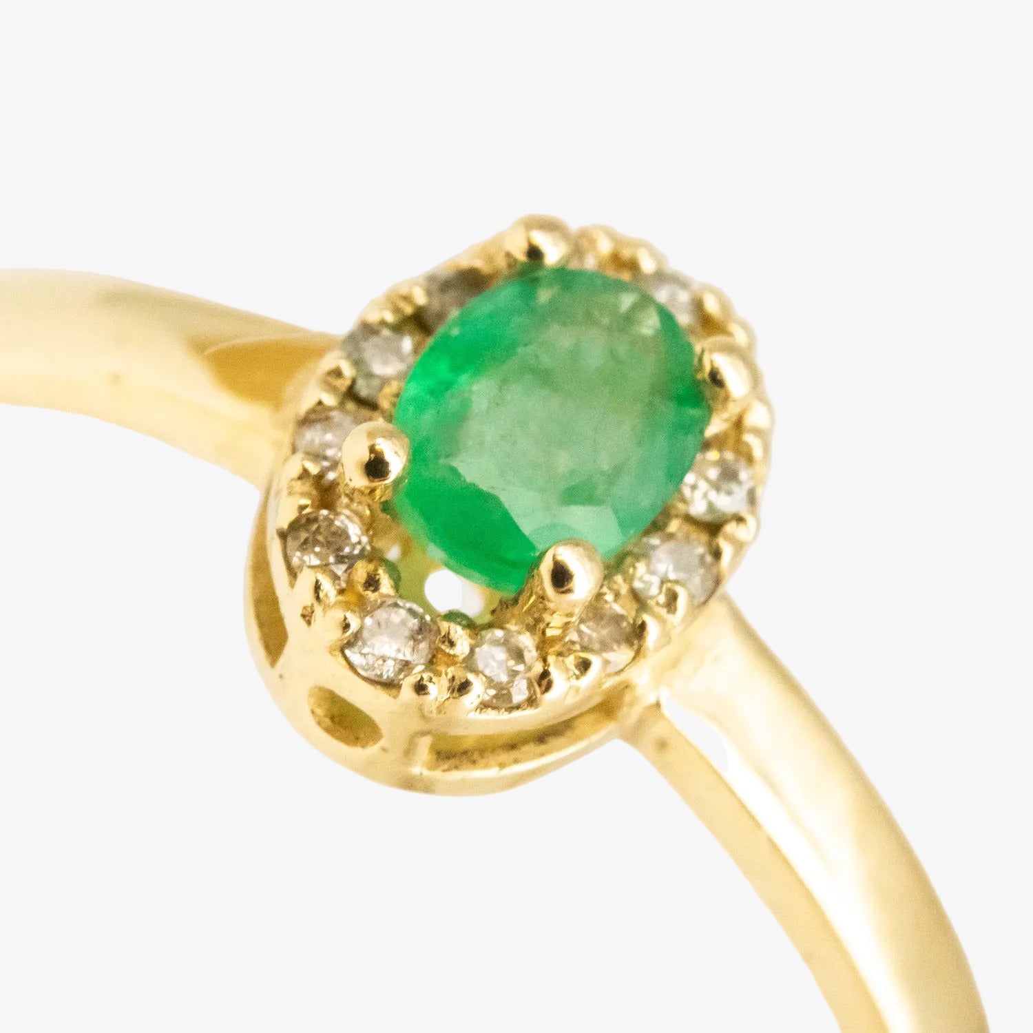 Sortija de oro amarillo de 14 kt. con doce diamantes y una esmeralda de 0.30 ct.